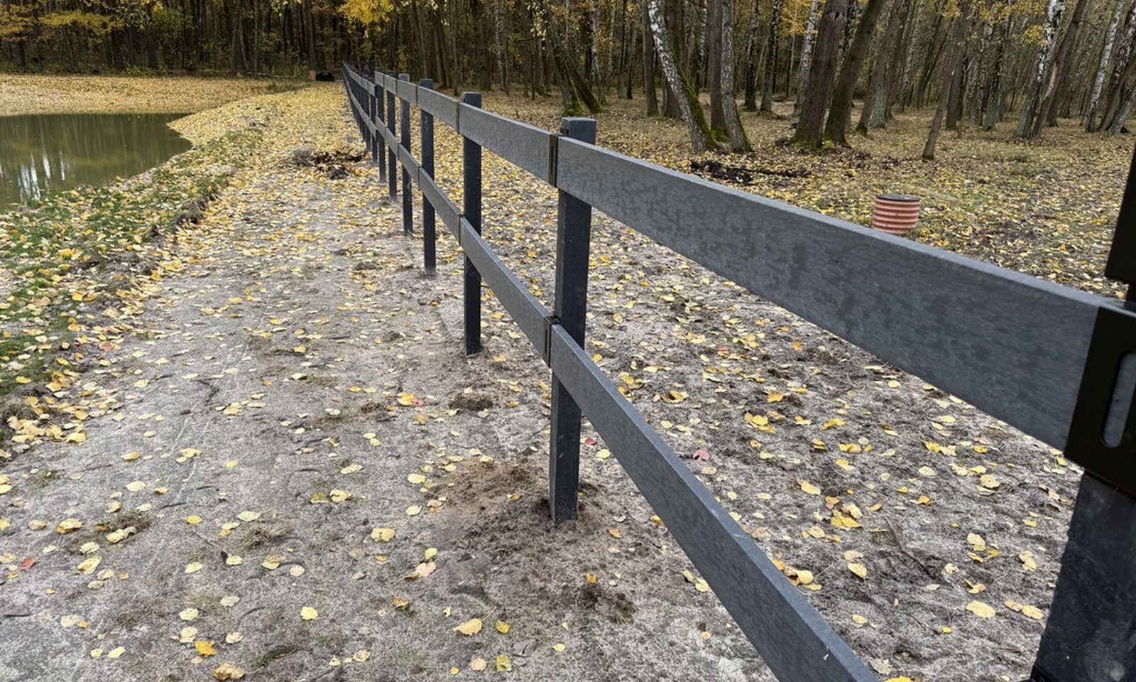 Dwurzędowe ogrodzenie EcoFarm z desek kompozytowych na grobli jesienią